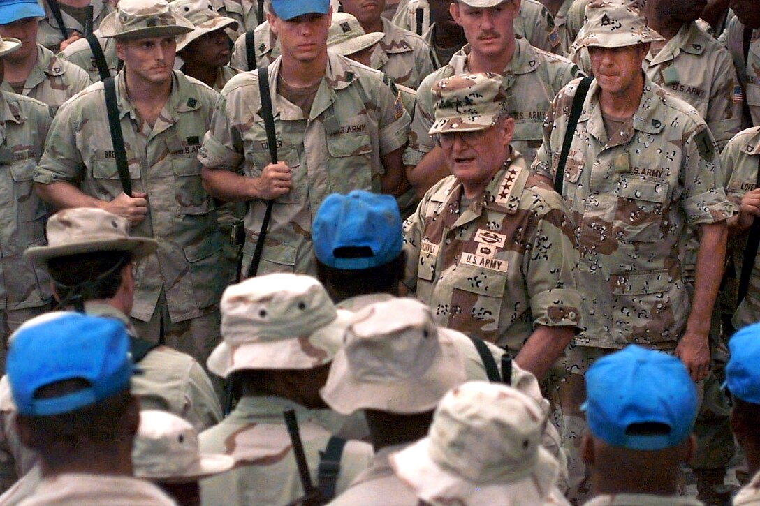 U.S. Army Gen. John M. Shalikashvili, then-chairman of the Joint Chiefs of Staff, is surrounded by soldiers operating on Sword Base, Mogadishu, Somalia, Dec. 19, 1993, during his tour of United Nationsl Operations in Somalia II operations. UNOSOM II is in direct support of Operation Restore Hope.