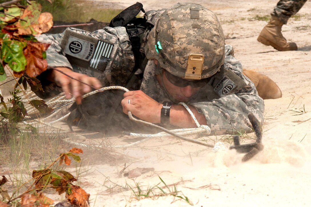 An Army combat engineer clears potential mines leading up to a wire obstacle with the aid of a grappling hook during a training exercise on Fort Bragg, N.C., July 21, 2011.