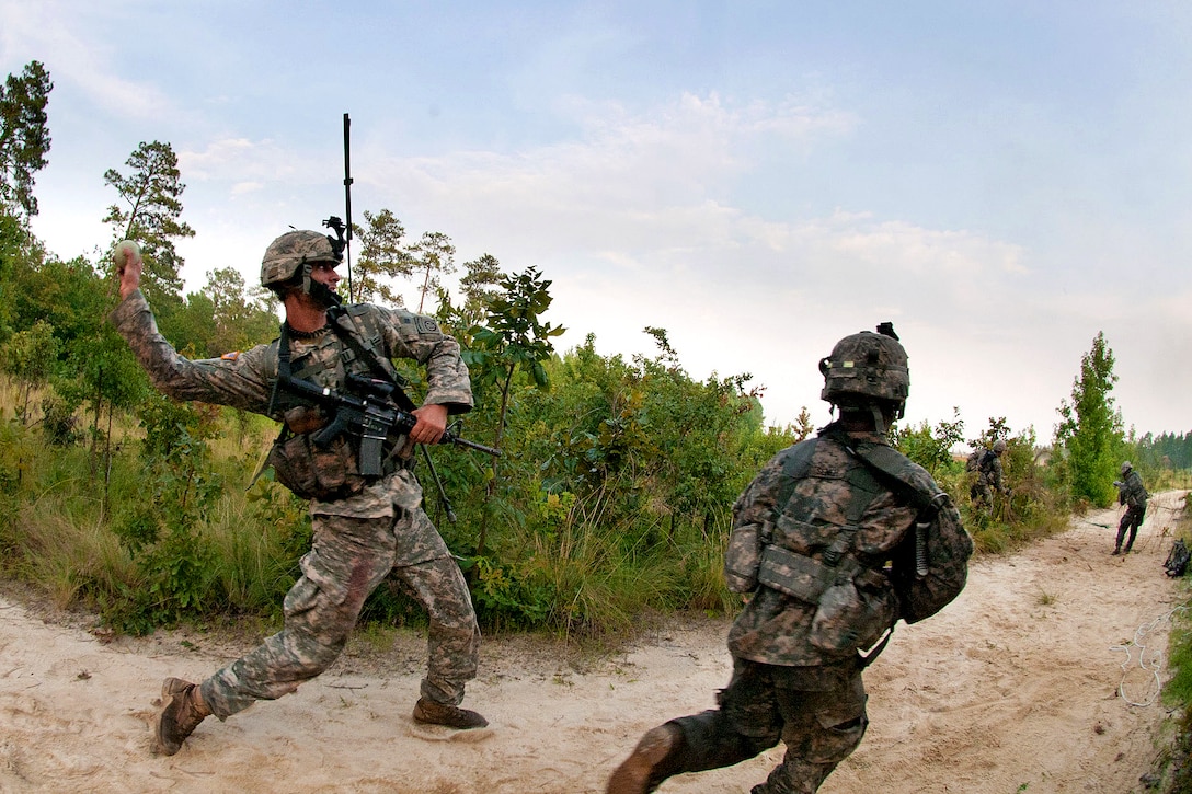An Army combat engineer throws a smoke grenade to provide cover for his engineers as they advance forward to establish a firing position during a training exercise on Fort Bragg, N.C., July 21, 2011.