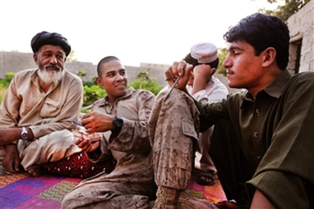 U.S. Marine Corps Sgt. Jose Hernandez interacts with a local elder and his family during a security patrol in the Garmsir District in Afghanistan's Helmand province on July 8, 2011.  Hernandez is assigned to Weapons Company, 1st Battalion, 3rd Marine Regiment, Combined Anti-Armor Team 1.  