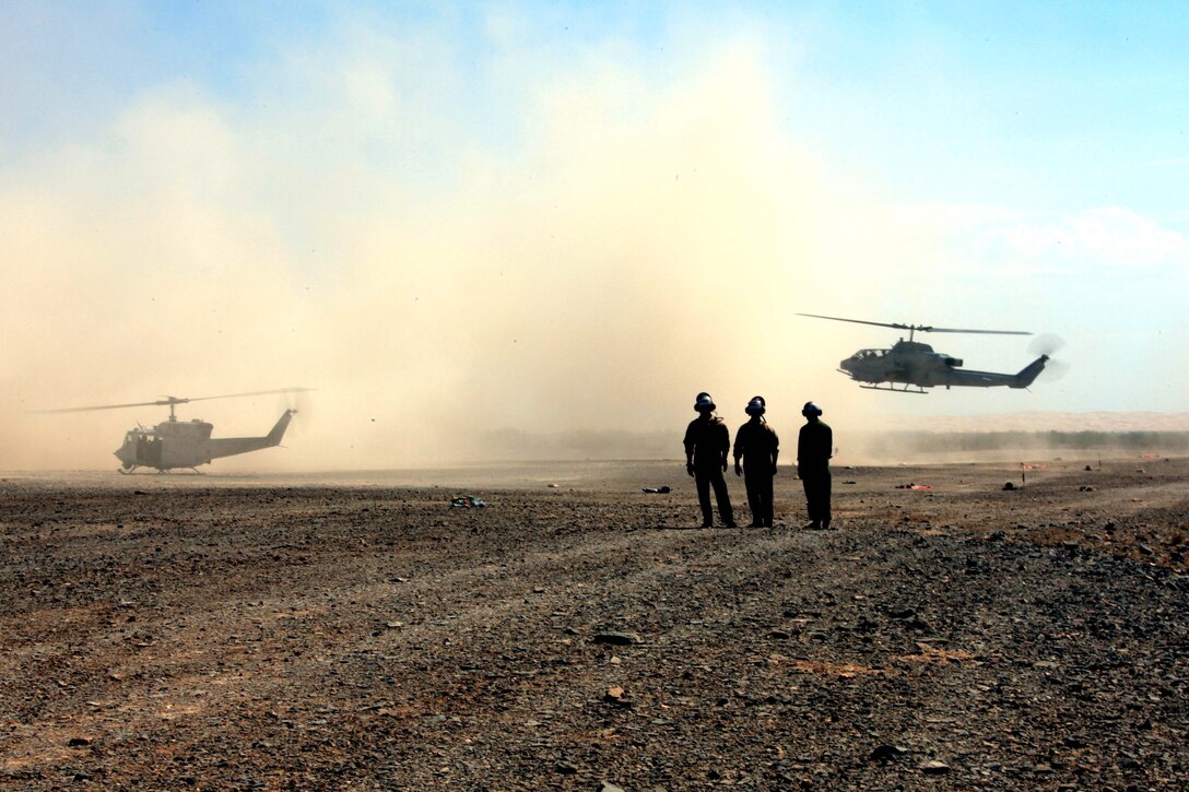 Marines with MAG-49 watch a UH-1N Huey and a Bell AH-1 Super Cobra land at a forward arming and refueling point outside Marine Corps Air Station Yuma, Ariz., July 25. At the FARP, Marines refueled and armed the helicopters for training missions during Operation Javelin Thrust 2011.