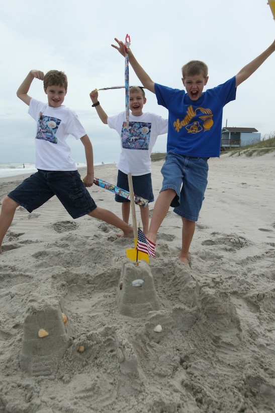 (From left to right) James, Philip and Peter Shippy, military children, celebrate for winning second place during a sandcastle building competition at Onslow Beach, hosted by Harriote B. Smith Library aboard Marine Corps Base Camp Lejeune, July 26. More than 67 Summer Reading Program participants attended the event.