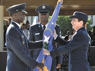 Air Force Gen. Edward A. Rice Jr., left, presents the 502nd Air Base Wing guidon to Air Force Brig. Gen. Theresa Carter as Command Chief Master Sgt. Juan Lewis, center, observes during Monday’s change of command ceremony at MacArthur Parade Field. (U.S. Air Force photo by/L.A. Shively)