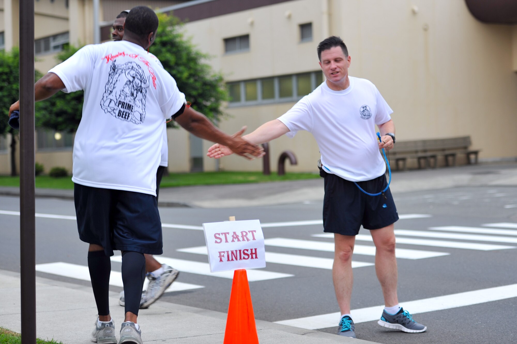 YOKOTA AIR BASE, Japan -- Master Sgt. Kendall Prude, 374th Civil Engineer Squadron first sergeant, is congratulated as he finishes an 8-mile run at Yokota Air Base, Japan, July 27, 2011. Airmen from the 374th CES participated in the first annual "Running of the Bulls" event to boost squadron morale and promote physical fitness. (U.S. Air Force photo/Airman 1st Class Krystal M. Garrett)