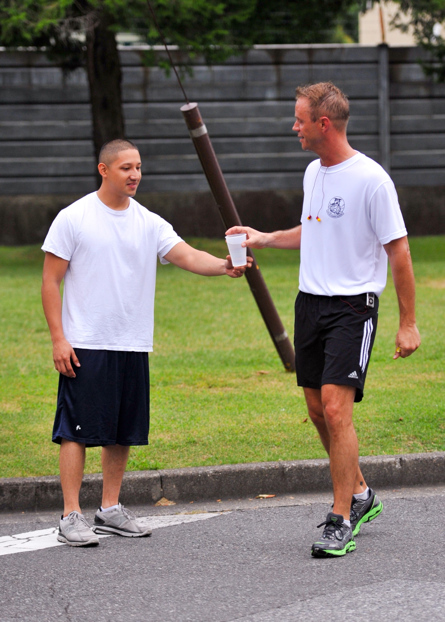 YOKOTA AIR BASE, Japan -- Staff Sgt. Daniel Vera-Erazo, 374th Civil Engineer Squadron structures craftsman, hands a cup of water to Lt. Col. Wade Rawlins, 374th Civil Engineer Squadron commander, during the 5.5 mile mark of the first annual "Running of the Bulls" event at Yokota Air Base, Japan, July 27, 2011. Airmen stood at water stations along the way to assist runners. (U.S. Air Force photo/Airman 1st Class Krystal M. Garrett)