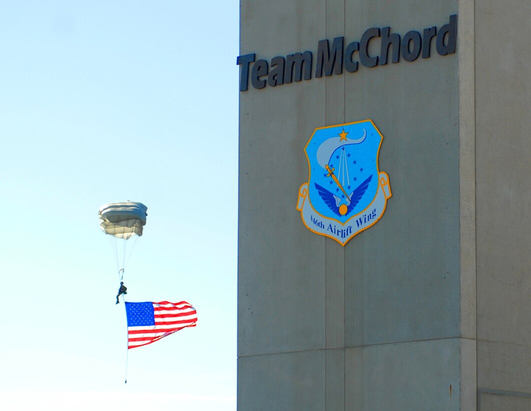 A special tactics Airman parachutes from the sky carrying an American flag during the opening ceremonies for the 2011 Air Mobility Rodeo at Joint Base Lewis-McChord, Wash., July 24. The Rodeo is a biennial, international airlift competition hosted by AMC which allows the United States and allied air forces to enjoy camaraderie while sharpening each other’s skills. (U.S. Air Force photo/Staff Sgt. Carolyn Herrick)