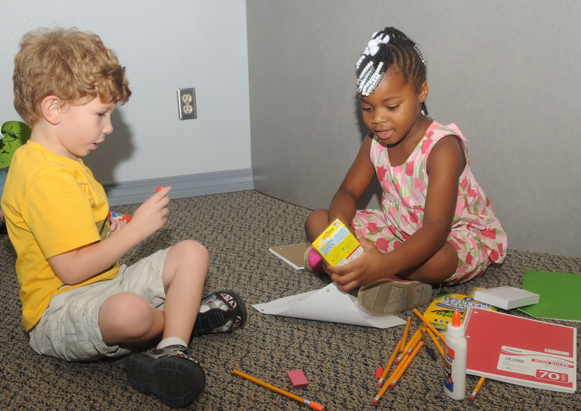 Paden Gunter and Amiyah Garrett, both age 5, sort through school supplies they received at the Back to School night at Hoban Hall on Barksdale Air Force Base, La., July 25.  School supplies were donated and distributed by Friends of Family Support, an organization that supports programs given through the Airman and Family Readiness Center. (U.S. Air Force photo/Senior Airman Kristin High)(RELEASED)