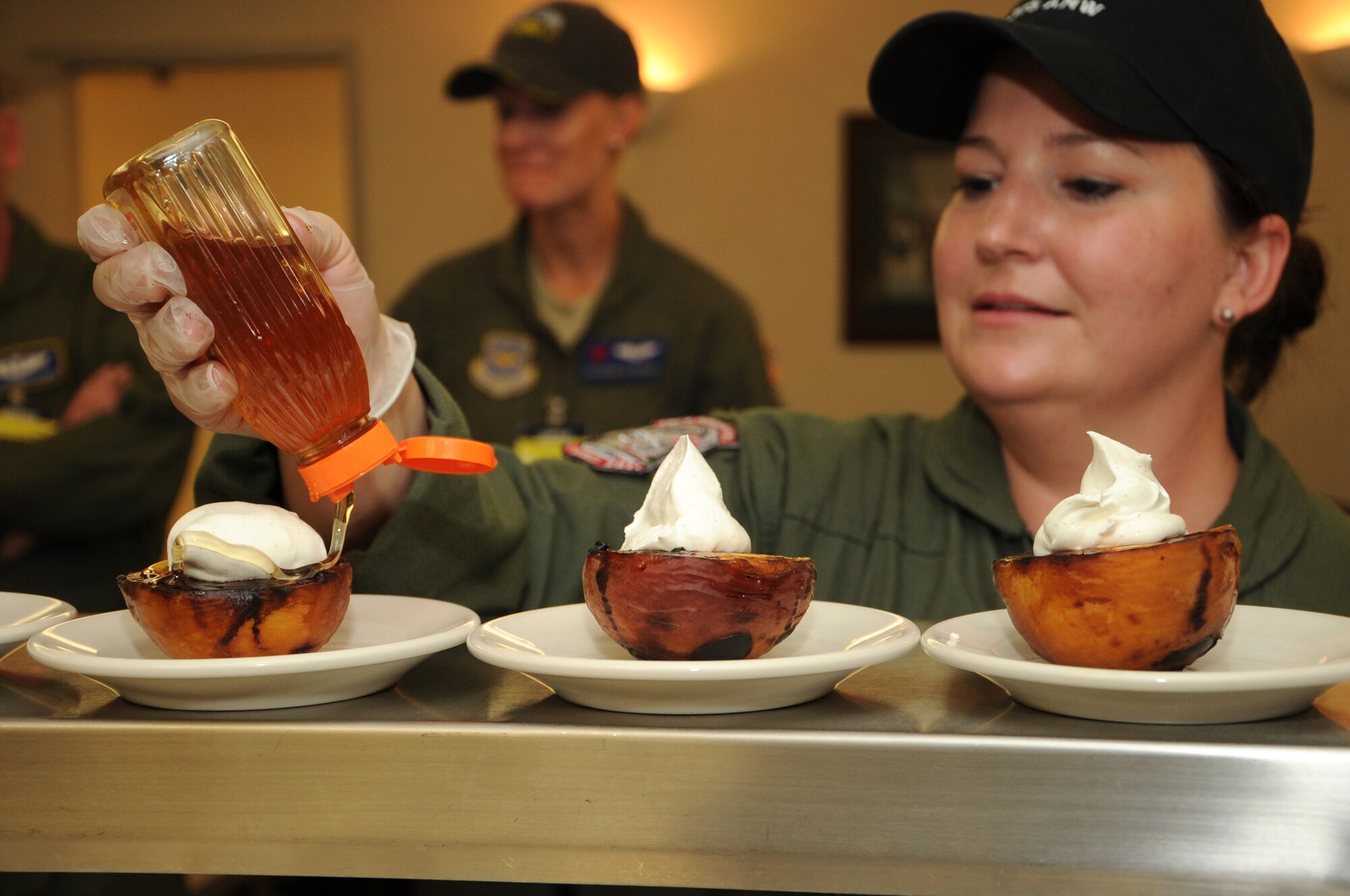 U.S. Air Force Tech. Sgt. Danielle Sloan, a flight attendant, from Scott Air Force Base, Ill., squeezes honey  on peaches during the culinary skills competition at Air Mobility Rodeo, Joint Base Lewis-McChord, Wash., on July 25, 2011. Rodeo is the U.S. Air Force's and Air Mobility Command's premier international combat skills and flying operations competition designed to develop and improve techniques, procedures, and interoperability, while optimizing international mobility partnerships and enhancing mobility operations. The flight attendant challenge at Rodeo consists of a timed aircraft evacuation and culinary skills competition. (U.S. Air Force photo by Tech. Sgt. Christine Jones/Released)