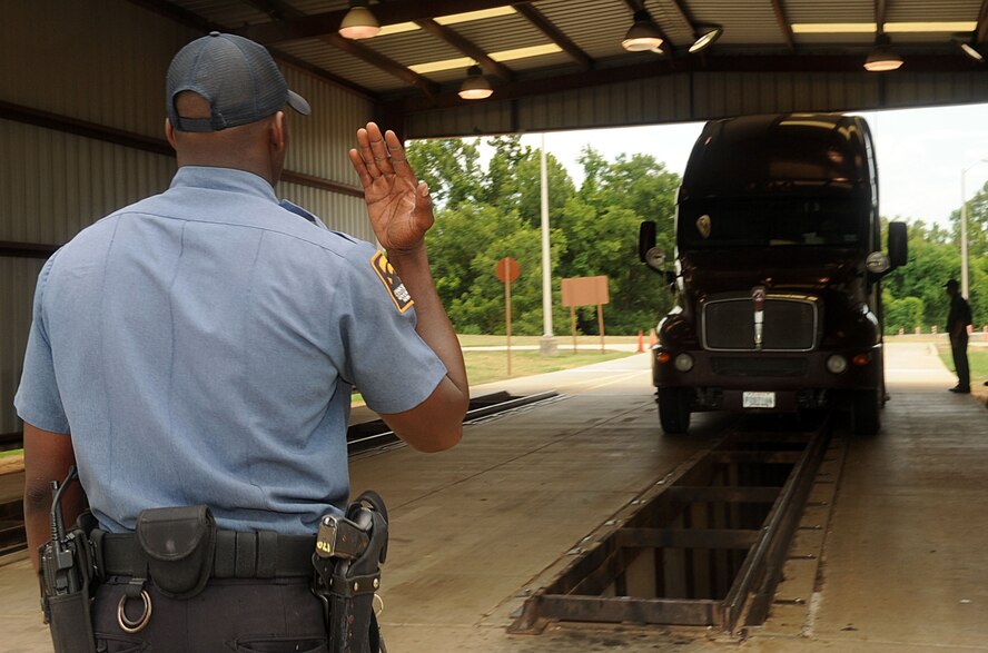 Derrick Trotter, Pinkerton Government Services Incorporated gate guard, signals a truck to proceed forward for an inspection at the East Gate on Barksdale Air Force Base, La., July 25. The guards inspect vehicles to ensure they are compliant with installation rules and regulations prior to allowing entry to the installation. (U.S. Air Force photo/SeniorAirman Kristin High)(RELEASED)