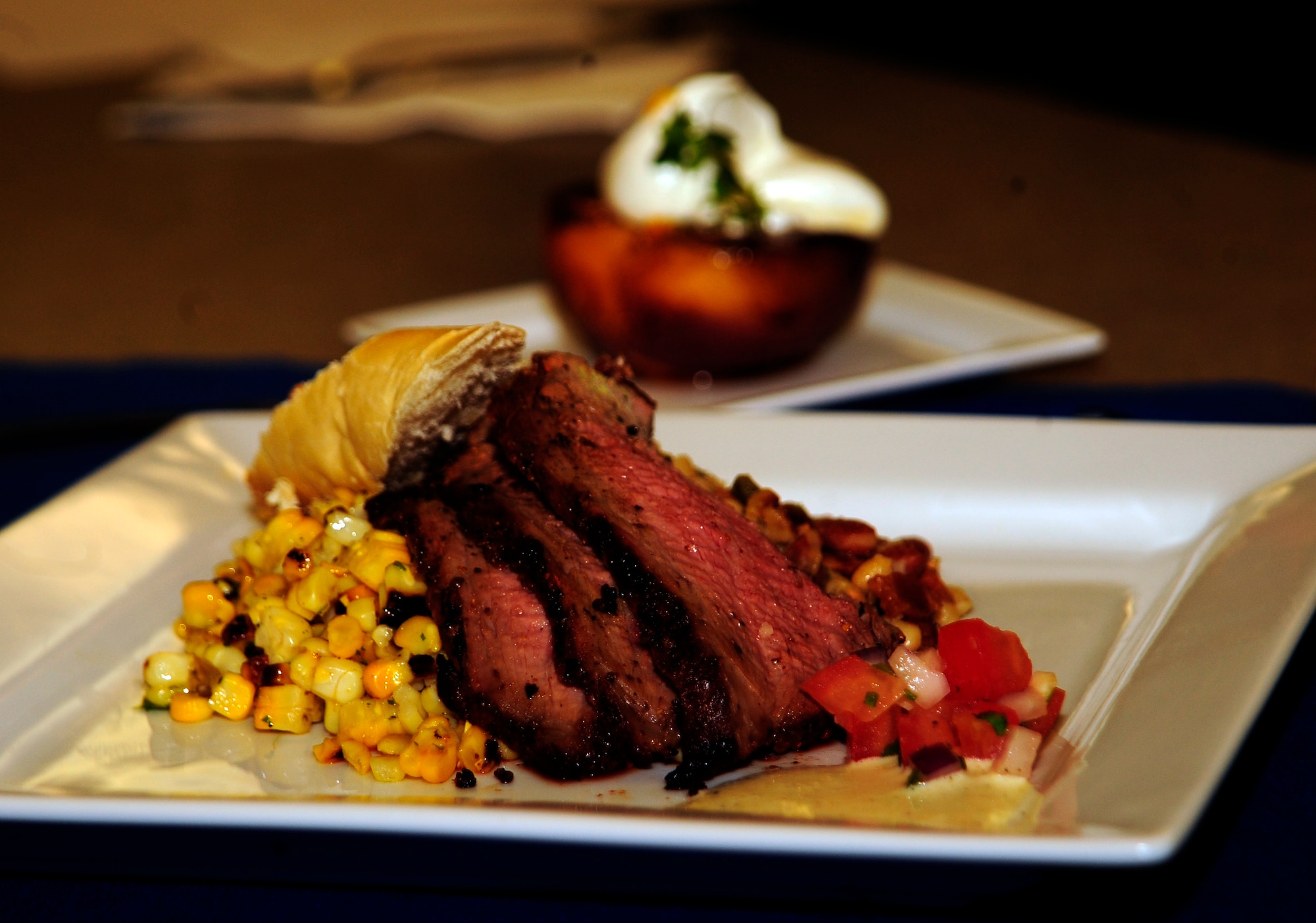 Tri-tip steak, ranch-style beans, roasted corn and a grilled peach sit on a plate, July 25, 2011, as part of the first-ever Air Force flight attendant culinary competetion at Air Mobility Rodeo 2011, Joint Base Lewis-McChord, Wash. The judges, rated the meals based on taste, presentation and creativity. Five, two-person teams from around the Air Force competed in the event. This meal was prepared by the only Total Force team, Tech. Sgt. Dani Sloan, a Reservist, and Staff Sgt. Amy Gillilan from the 73rd and 54th Airlfit Squadrons, Scott Air Force Base, Ill., respectively. (U.S. Air Force photo/Staff Sgt. J.G. Buzanowski)