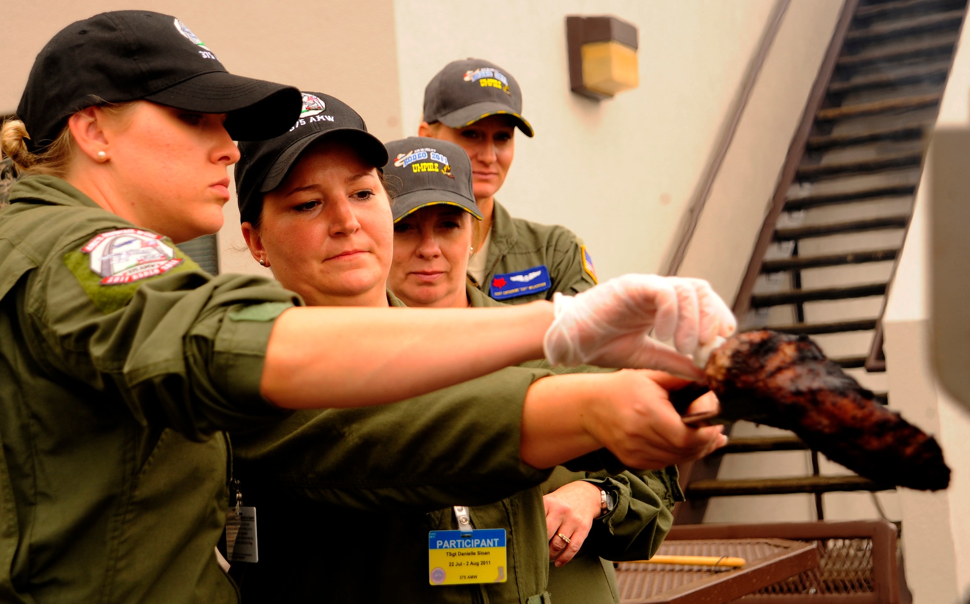 Staff Sgt. Amy Gillilan (left) and Tech. Sgt. Dani Sloan (center left) check the temperature on their tri-tip, July 25, 2011, as part of the first-ever Air Force flight attendant culinary competetion at Air Mobility Rodeo 2011, Joint Base Lewis-McChord, Wash. The judges, Chief Master Sgt. Seina Enwright (center right) and Staff Sgt. Cat Wilkerson observed the competition to ensure all meals were prepared safely. In addition, the judges rated the meals based on taste, presentation and creativity. Five, two-person teams from around the Air Force competed in the event. The only Total Force team, Sloan, a Reservist, and Gillilan are from the 73rd and 54th Airlfit Squadrons, Scott Air Force Base, Ill., respectively. (U.S. Air Force photo/Staff Sgt. J.G. Buzanowski)