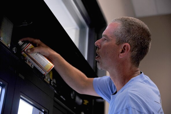 SEYMOUR JOHNSON AIR FORCE BASE, N.C.- John Humphries sprays Teflon silicone lubricant on an automated door's wheels after repairing a broken motor on the door here, July 25, 2011. Spraying lubricant on the wheels helps the door slide with ease. Humphries is an Automated Entrances Inc. service technician and a native of Kenly. (U.S. Air Force photo by Senior Airman Whitney Lambert/ Released)