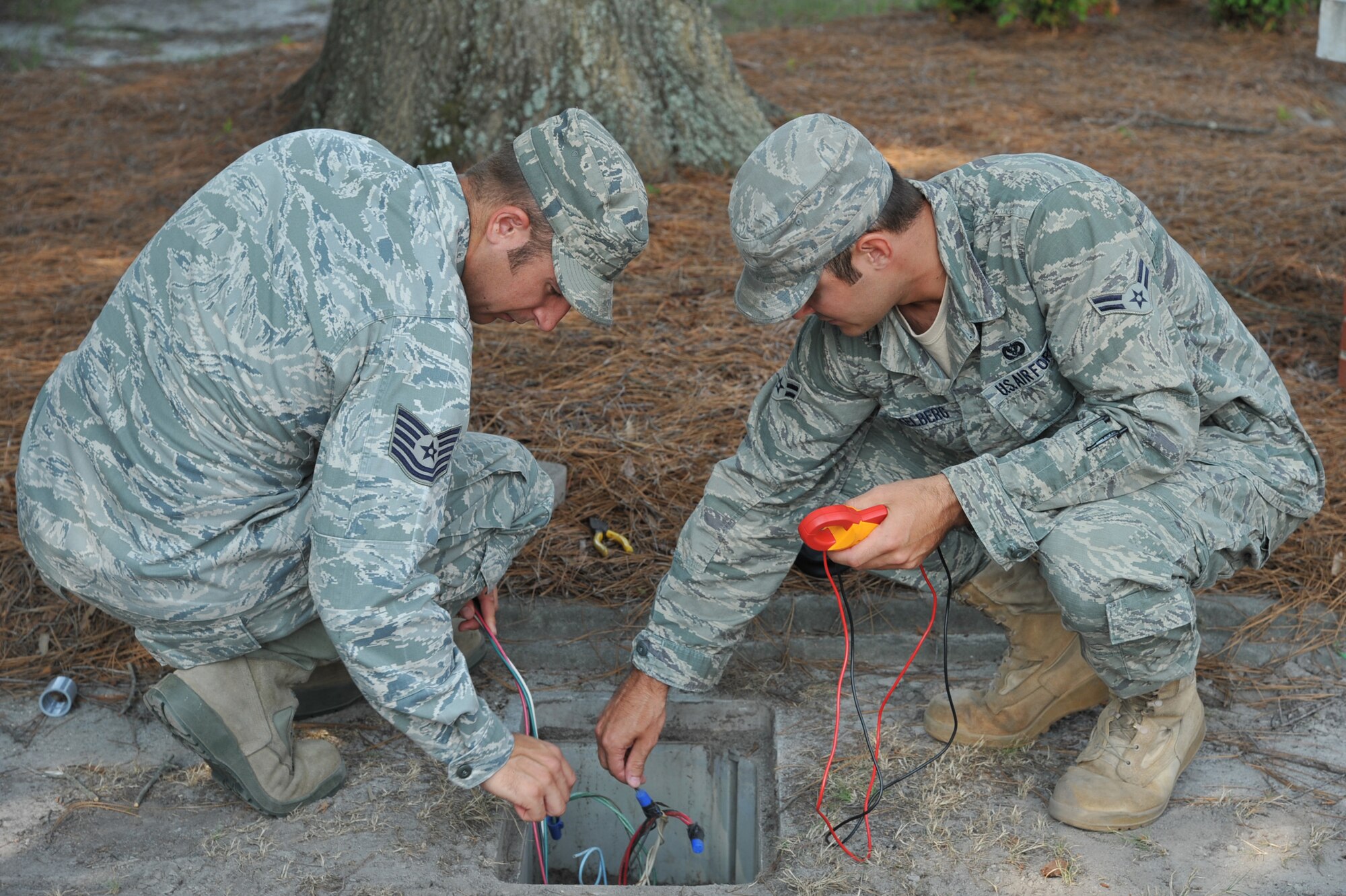 SEYMOUR JOHNSON AIR FORCE BASE, N.C.- Tech. Sgt. Jeffrey Mooney and Airman 1st Class Kyle Dunkelberg check for power in a handhold here, July 25, 2011. The handhold contains circuits that run underground from a transformer to supply power to buildings on base. Mooney is a 4th Civil Engineer Squadron (CES) electrical systems craftsman and a native of Dayton. Dunkelberg is a 4th CES electrical systems journeyman and a native of Waddington, N.Y. (U.S. Air Force photo by Senior Airman Whitney Lambert/ Released)