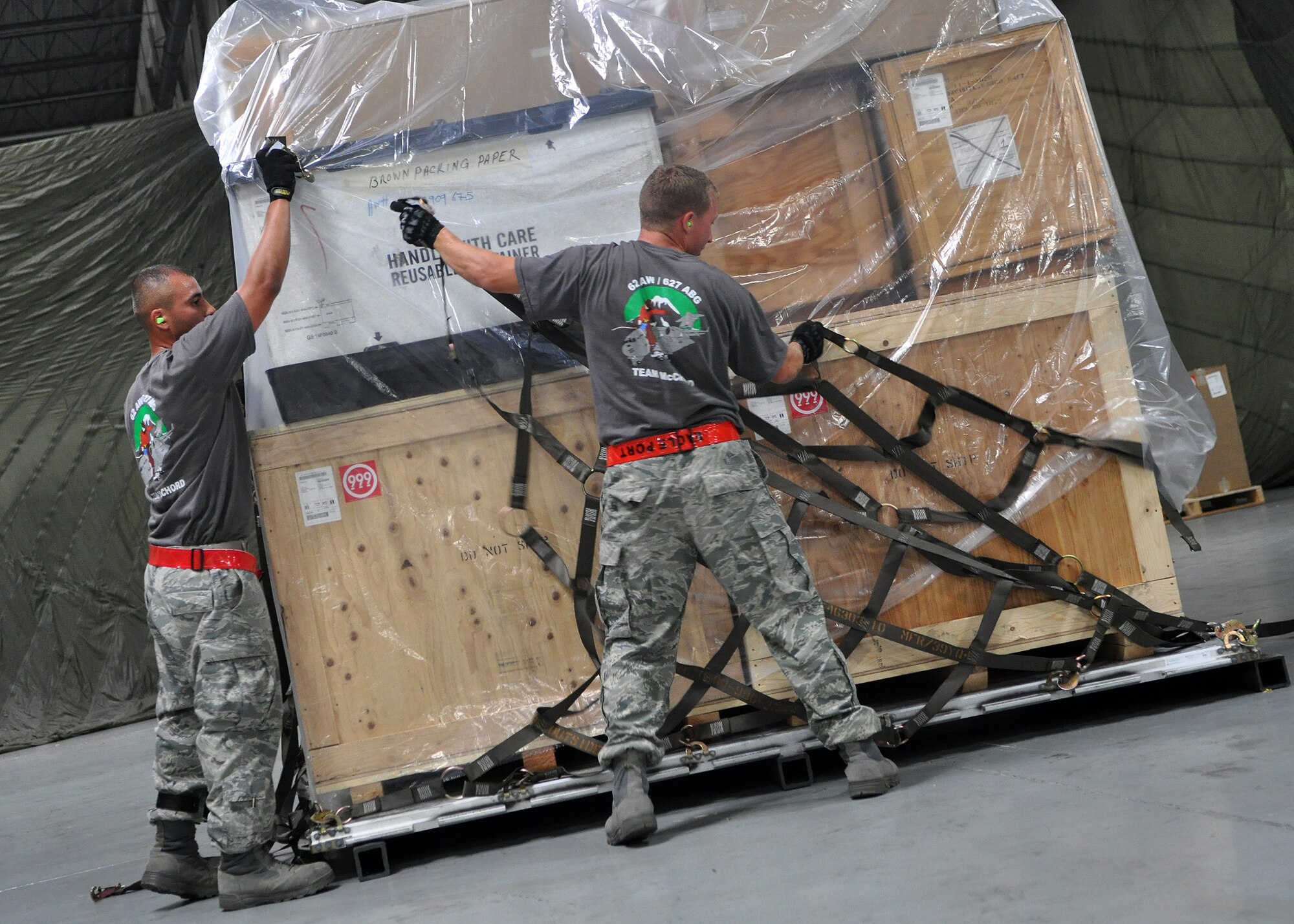 Staff Sgts. Jason Caro, left, and Mark Robertson, both 62nd Aerial Port Rodeo team members, secure a net to a boxes of cargo during a pallet buildup competition as part of Air Mobility Rodeo July 25, 2011, at Joint Base Lewis-McChord, Wash. Rodeo is a  bi-annual competition that encompasses all aspects of Air Mobility Command, including aerial port, aeromedical evacuation, maintenance, security forces, and financial management. (U.S. Air Force photo/Airman 1st Class Leah Young)