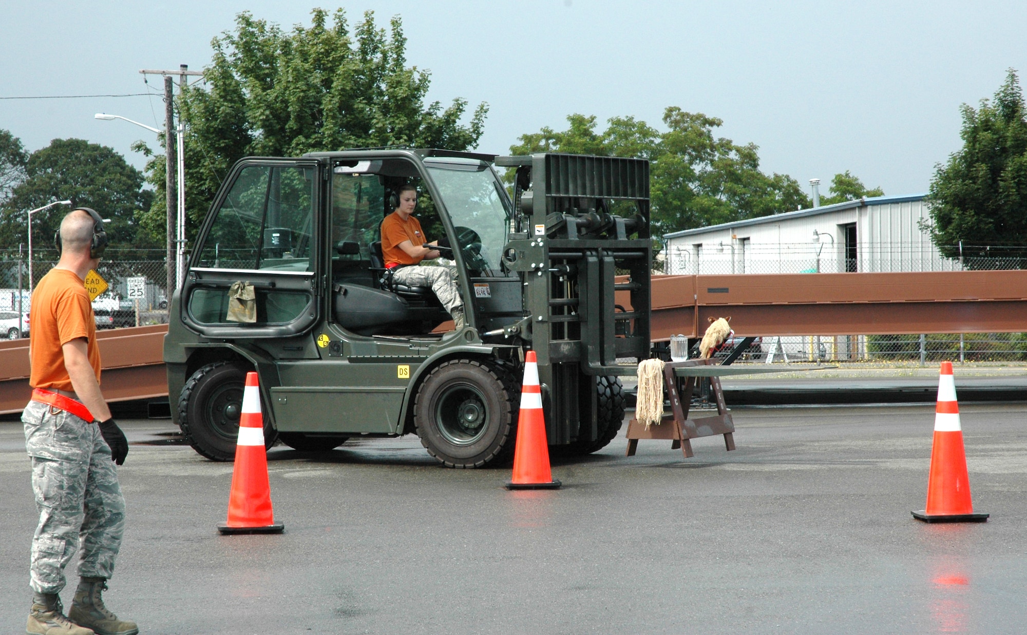 Senior Airman Janelle Marshall uses a delicate touch when moving a pitcher of water on a saw horse during the 10K forklift event July 25 for the 446th Airlift Wing's Rodeo aerial port team, as teammate Tech. Sgt. Joshua Warbiany provides direction. The Reservists' challenge was to demonstrate proficiency in maneuvering a 10K forklift through a driving course, while balancing objects on the lift during Air Mobility Command’s Rodeo, July 24-29 at McChord Field, Wash. (U.S. Air Force photo by Sandra Pishner)