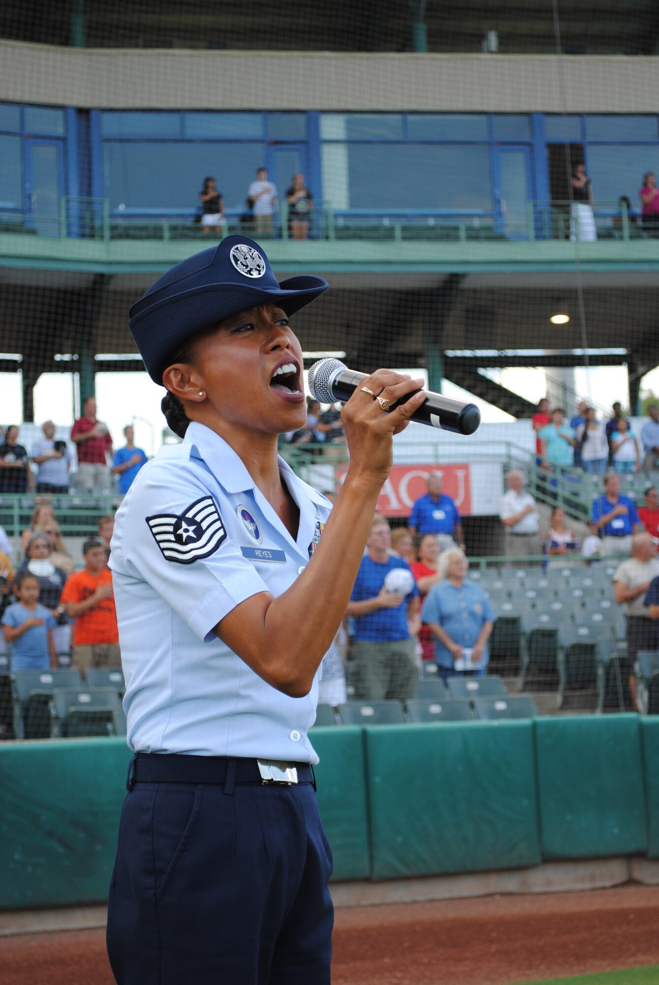The minor league baseball crowd stands as Technical Sgt. Hilary Reyes, a 433rd Training Squadron military training instructor, sings “The Star-Spangled Banner” during the opening ceremony of the San Antonio Missions Military Appreciation Night, July 20, 2011, at Nelson Wolff Stadium. Although the U.S. Air Force Reserve NCO has performed at various local and international events throughout her combined 19-years of military service, singing the national anthem at the minor league baseball game Wednesday night was her first time performing at a public sporting event. (U.S. Air Force photo/senior Airman Luis Loza Gutierrez)