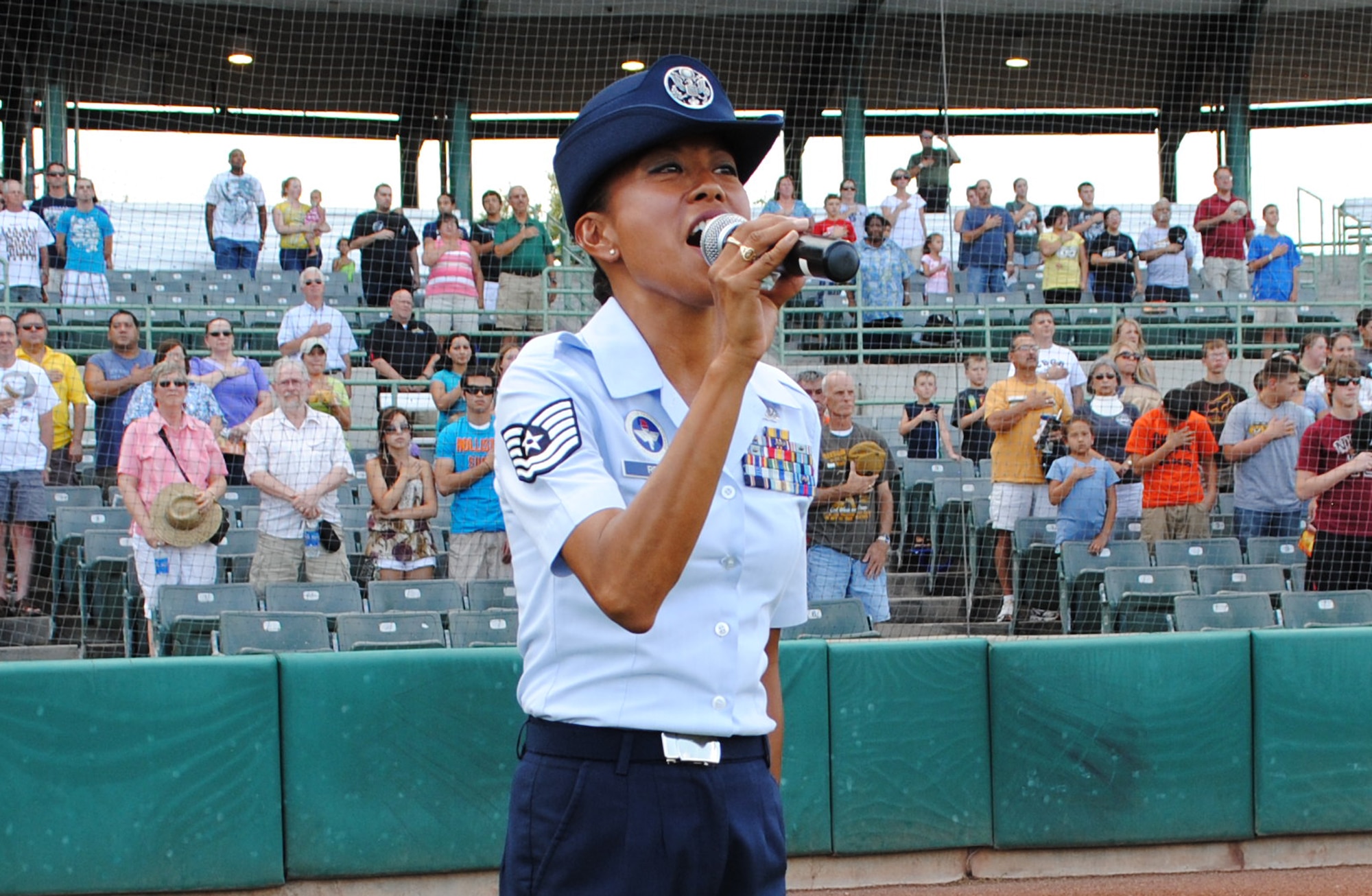 The minor league baseball crowd stands as Technical Sgt. Hilary Reyes, a 433rd Training Squadron military training instructor, sings “The Star-Spangled Banner.” Reyes performed during the opening ceremony of the San Antonio Missions Military Appreciation Night, July 20, 2011, at Nelson Wolff Stadium. Although the U.S. Air Force Reserve NCO, has performed at various local and international events throughout her combined 19-years of military service, singing the national anthem at the minor league baseball game Wednesday night was her first time performing at a public sporting event. (U.S. Air Force photo/senior Airman Luis Loza Gutierrez)