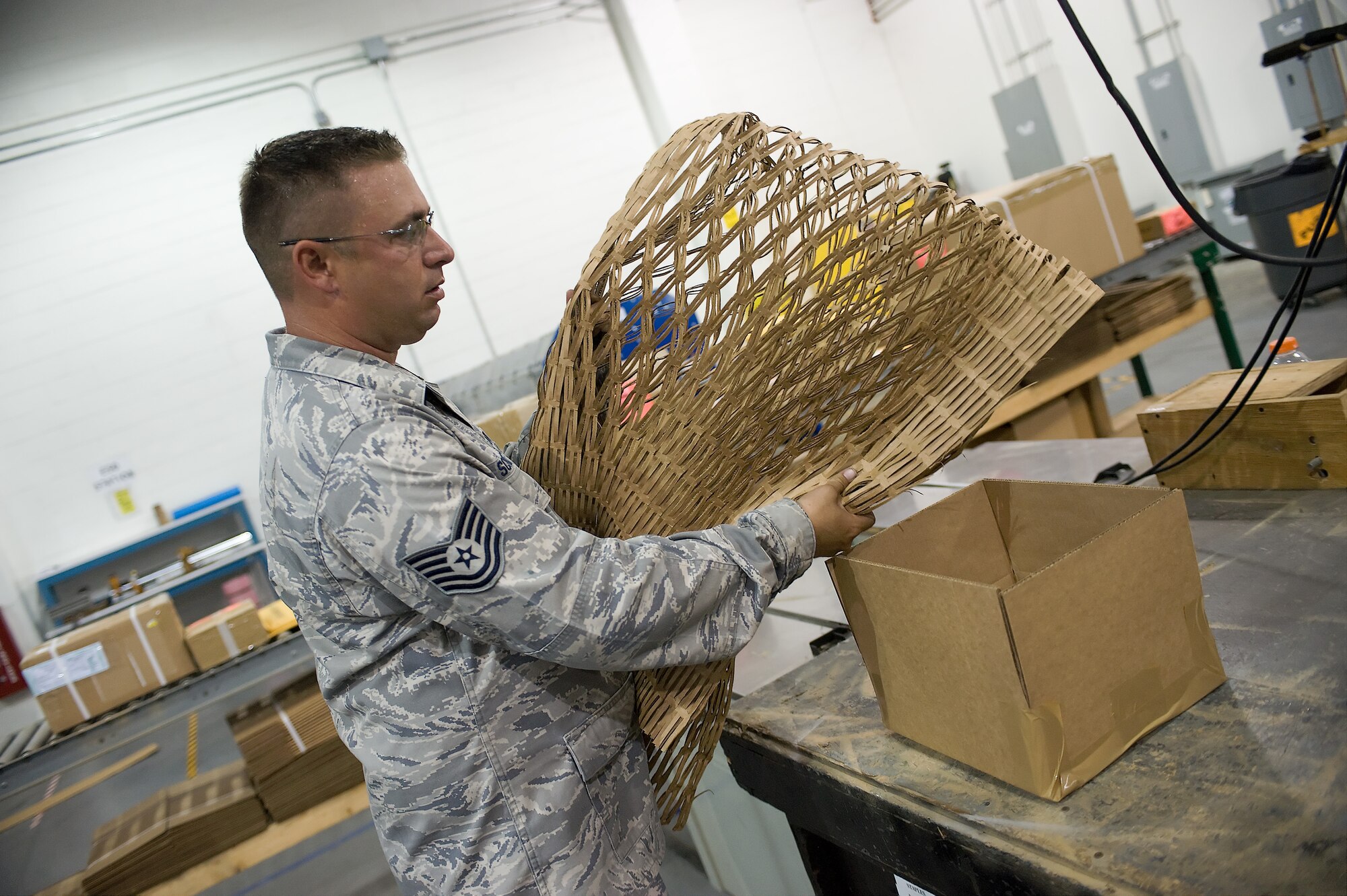 Tech. Sgt. Mark Scribner, the NCO in charge of packing and crating with the 436th Aerial Port Squadron, uses recycled cardboard as protection for items ready to ship July 20, 2011, at Dover Air Force Base, Del. The packing and crating shop builds pallets and crates to fit any object that flies on military aircraft. (U.S. Air Force photo by Steve Kotecki)