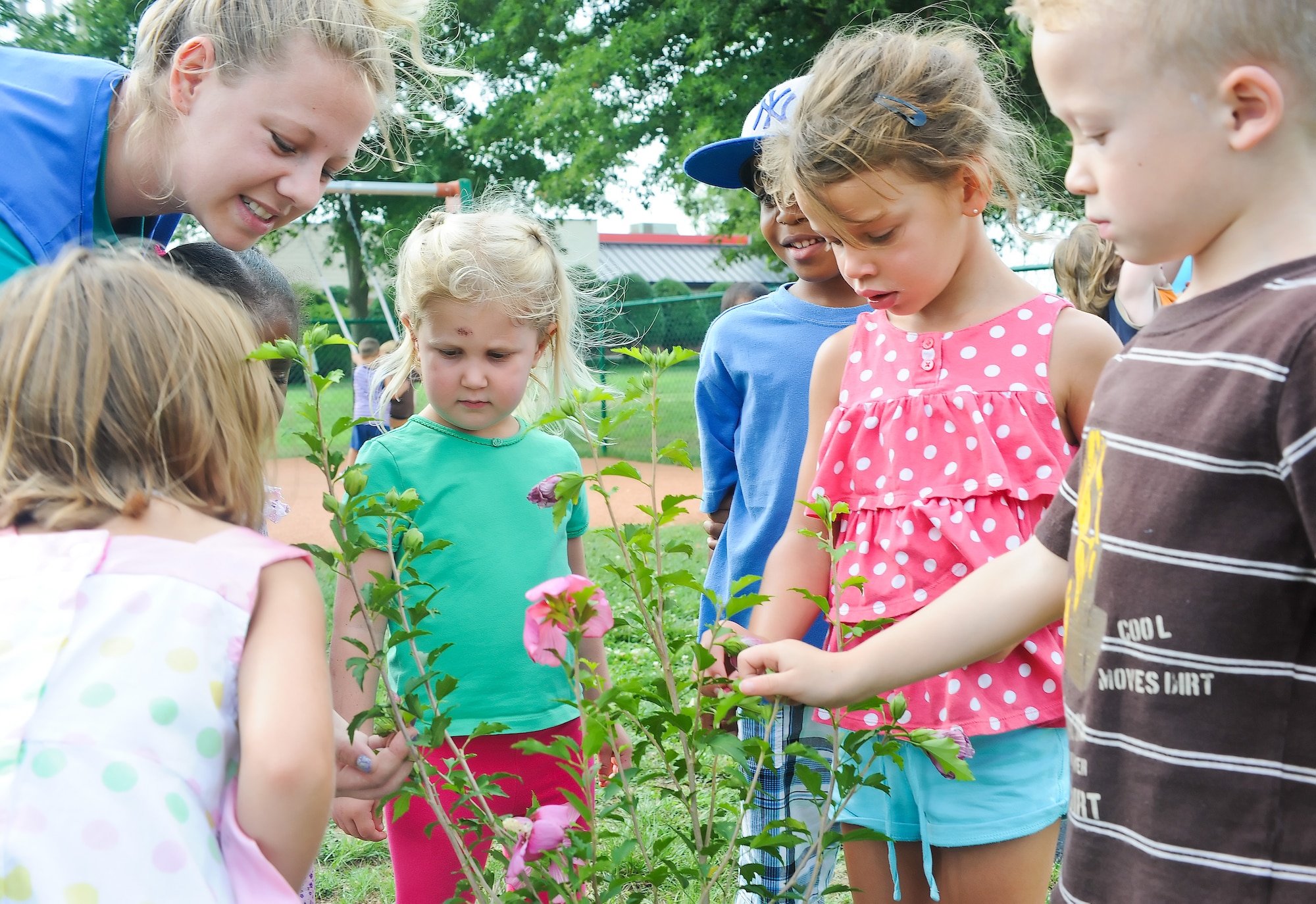 Angela Gideon, a staff member at the Child Development Center, and children from the CDC observe a flower July 25, 2011, at Dover Air Force Base, Del. The flower was planted as part of a gardening project, made possible by a grant from the Paul Newman "Newman's Own Competition" and the Fisher House, intended to teach children to respect and appreciate nature. (U.S. Air Force photo by Airman 1st Class Samuel Taylor)