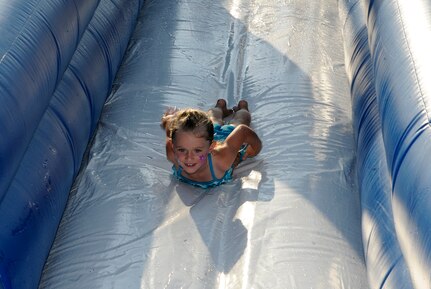 Four year old Brianna Stockwell, daughter of Staff Sgt. Seth Stockwell, slides down an inflatable water slide during the Water Park Wonderland event hosted by Balfour Beatty at Joint Base Charleston-Weapons Station, July 22.  The event kicked off the annual Resident Satisfaction Survey in which residents of JB CHS-WS base housing offer feedback to Balfour Beatty about the services being provided in the community. (U.S. Navy photo/ Mass Communication Specialist 3rd Class Brannon Deugan)