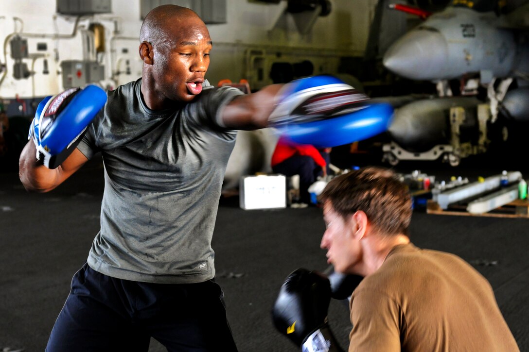 U.S. Navy Airman Rashard Lovelace practices boxing in the hangar bay aboard the aircraft carrier USS George H.W. Bush in the Arabian Gulf, July 19, 2011.