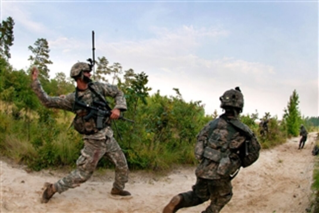 An Army combat engineer throws a smoke grenade to provide cover for his engineers as they advance forward to establish a firing position during a training exercise at Fort Bragg, N.C., on July 21, 2011.  