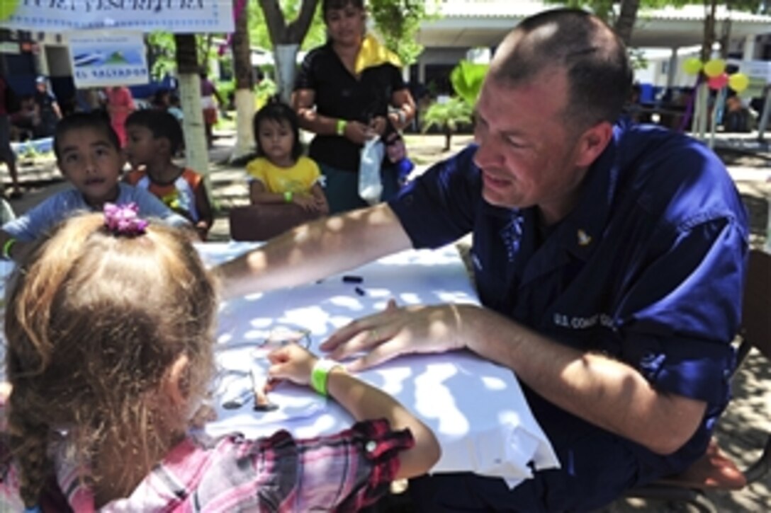 U.S. Coast Guard Master Chief Petty Officer Geoffrey Daly colors with a Salvadoran child at the Escuela Barra de Santiago medical site during Continuing Promise 2011 in Barra De Santiago,  El Salvador, July 23, 2011. Continuing Promise is a five-month humanitarian assistance mission to the Caribbean, Central and South America. Daly is a health service chief from Kodiak, Alaska.