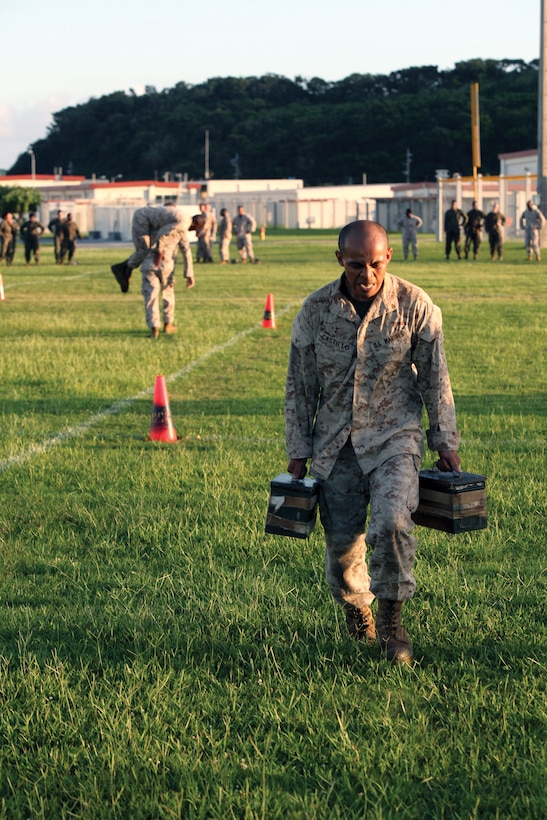 Cpl. Ron E. Castillo, a food service specialist with Headquarters and Service Battalion, Marine Corps Base Camp Butler, sprints while carrying two ammunition cans during the maneuver-under-fire lane, a portion of the Combat Fitness Test, July 27. The CFT was designed to test Marines' ability push themselves during high-stress situations.::r::::n::