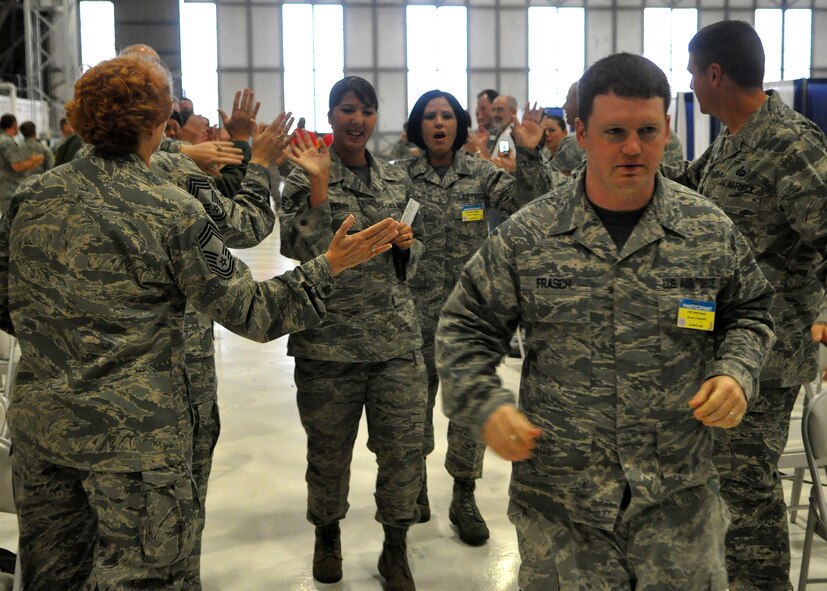 The 62nd Airlift Wing financial management Rodeo team receives high-fives from co-worker and Rodeo umpires during the morning "Pump-Up" as part of the Air Mobility Rodeo competition July 27, 2011, at Joint Base Lewis-McChord, Wash. The Pump-Up occurs every morning of Rodeo and consists of introductions and scores from the previous day. As the three-person teams from all around the world run down the center aisle, they are greeted with high-fives from co-workers and their team song ringing through the loud speakers. Rodeo is a bi-annual competition that encompasses all aspects of Air Mobility Command, including aerial port, aeromedical evacuation, maintenance, security forces, and financial management. (U.S. Air Force Photo/Airman 1st Class Leah Young)