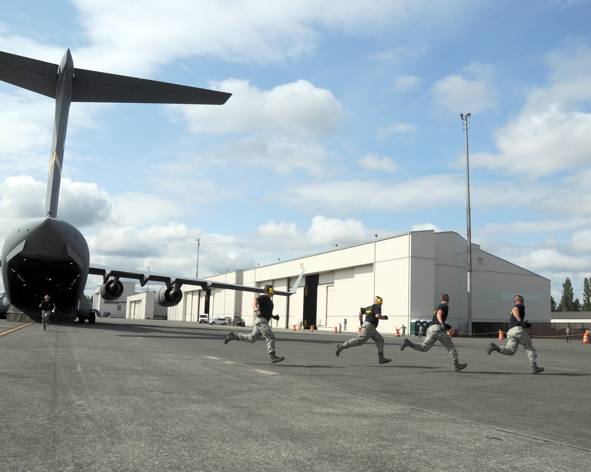 JOINT BASES LEWIS-MCCHORD, Wash. – 97th Logistics Readiness Squadron 2011 Air Mobility Command Rodeo team members from Altus Air Force Base, Okla., run to the finish line during the first part of the engine running on-load and off-load event during the 2011 AMC Rodeo July 27. This timed event was intended to simulate expedient on-load and off-load of cargo in a wartime environment using a five member team. (U.S. Air Force photo by Airman 1st Class Kenneth W. Norman / Released / 97th Air Mobility Wing Rodeo Public Affairs)