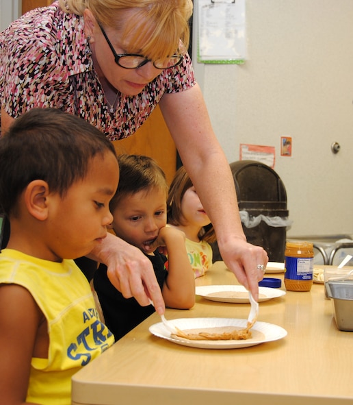 Beth Moss, the Health Promotion educator and manager at the Vance AFB Health and Wellness Center, shows children at the Child Development Center how to prepare breakfast “burritos” made of wheat tortillas, yogurt, peanut butter and various fruits. The children are participating in the “Fit Families” program designed to promote healthy eating and activity for all ages. (U.S. Air Force photo/ Jessica Gibson)