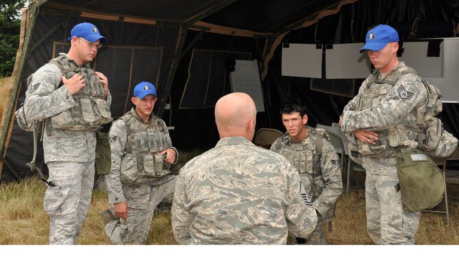 Master Sgt. William Gaskins, center, of the U.S. Air Expeditionary Center, gives the outbrief to Fairchild's 92nd Security Forces Squadron Airmen, from left, Staff Sgt. Matthew Grega, Senior Airman Richard Holder, Senior Airman Alexander Aun and Staff Sgt. Luke Wright. The team just completed a security forces tactics exercise July 25 as part of the Air Mobility Rodeo at Joint Base Lewis-McChord. (U.S. Air Force Photo/Tech. Sgt. Jennifer Buzanowski)