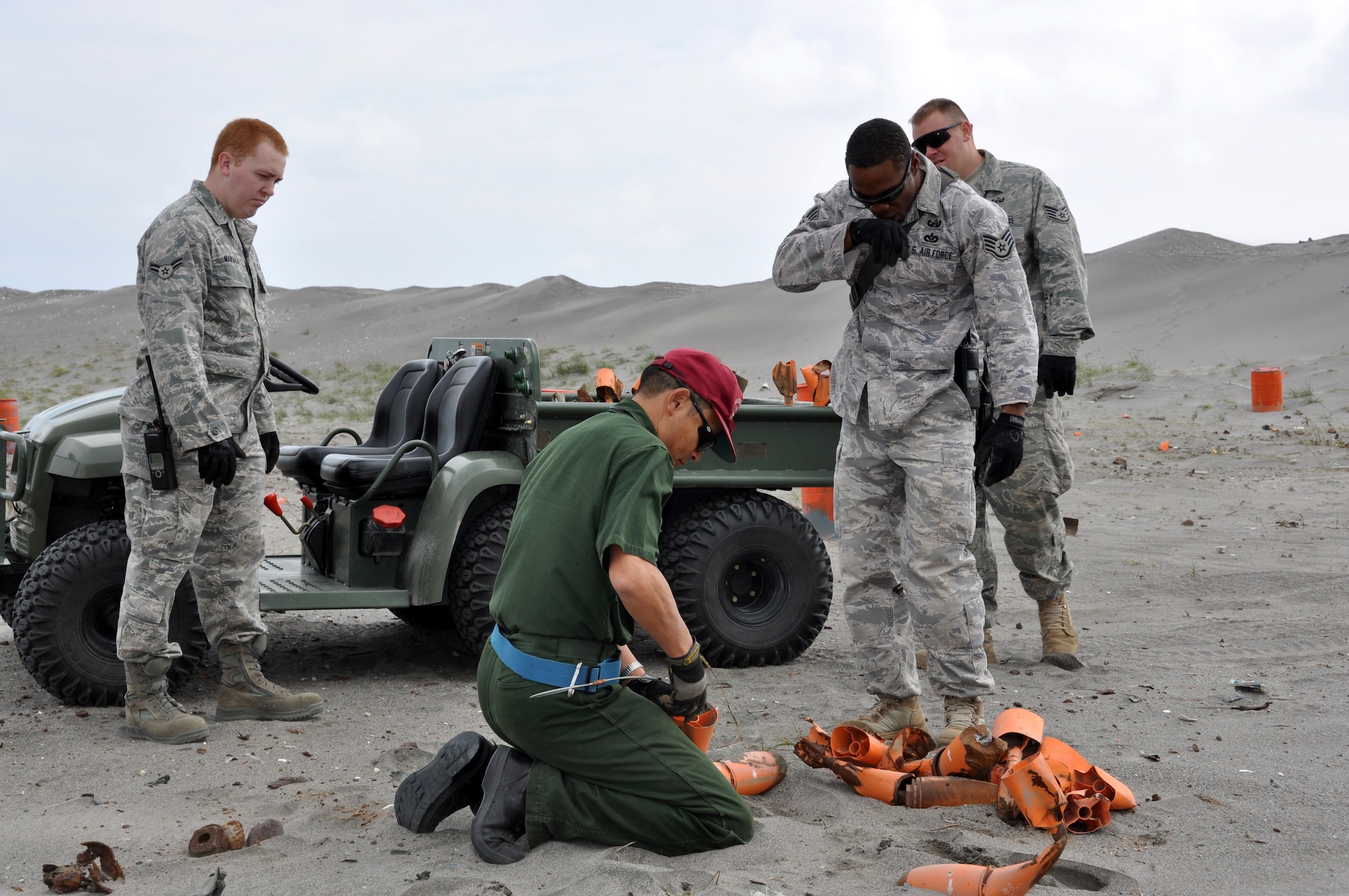 MISAWA AIR BASE, Japan – Airman First Class Michael Marsala, left, 35th Medical Squadron, and Staff Sgt. Kristopher Parker, right back, 35th Civil Engineer Squadron Explosive Ordnance Disposal technician, observe as Suzuki, kneeling, Japan Air Self-Defense Force member, and Staff Sgt. Michael Overton, right front, examines an expended Bomb Dummy Unit (BDU-33) at Draughn Range 22 July.  The range clearance happens about twice a month due to the amount of Bomb Dummy Units that are used and approximately six tons of expended ordinances are removed from the range.   (U.S. Air Force photo/ Tech. Sgt. Jeffrey Hansen)