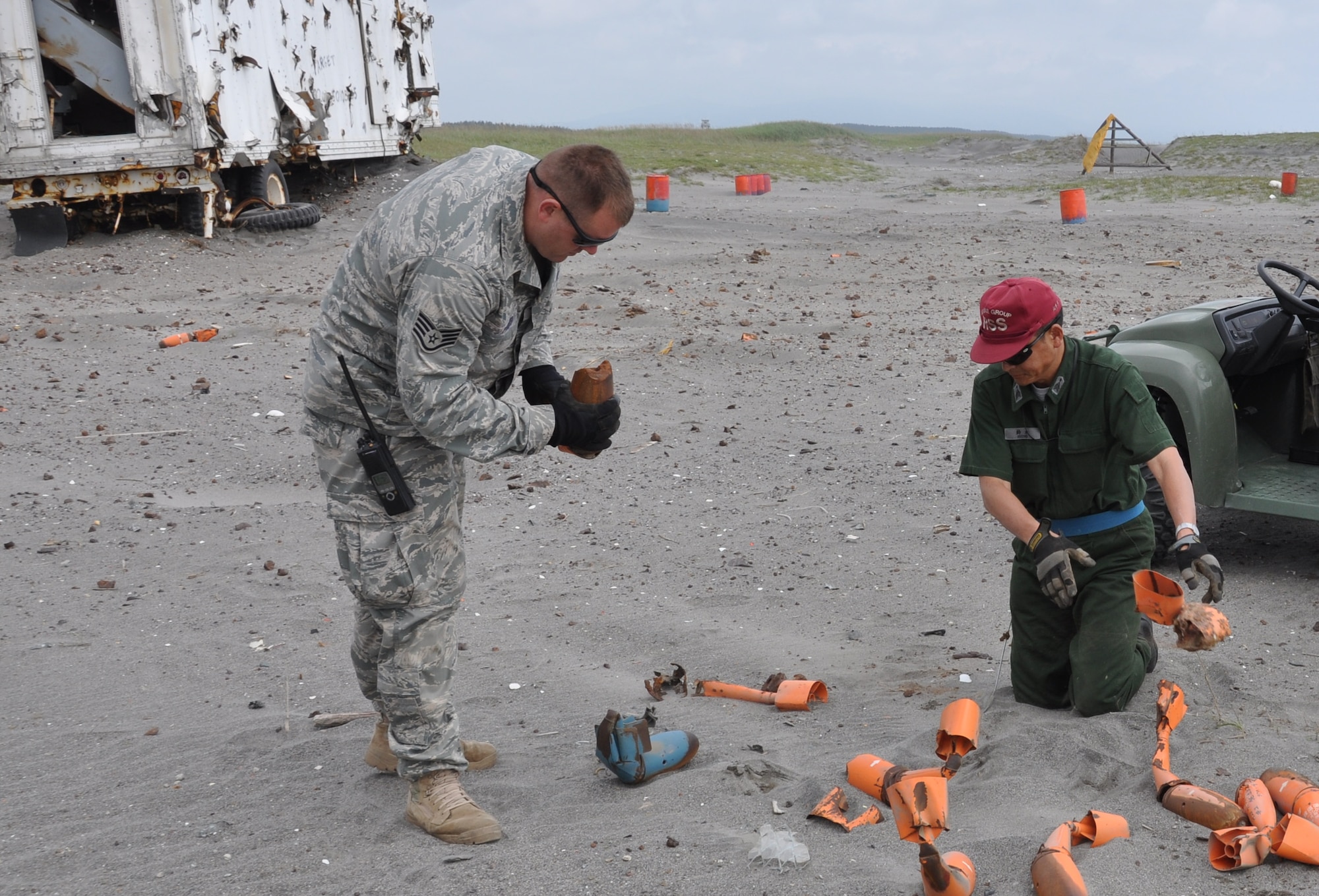MISAWA AIR BASE, Japan --Staff Sgt. Kristopher Parker, left, 35th Civil Engineer Squadron Explosive Ordinance Disposal technician, assists Suzuki, Japan Air Self-Defense Force member, on clearing expended ordinance cartridges from Draughn Range 22 July.  The range clearance happens about twice a month due to the amount of Bomb Dummy Units that are used and approximately six tons of expended ordinances are removed from the range.  (U.S. Air Force photo/Tech. Sgt. Jeffrey Hansen)