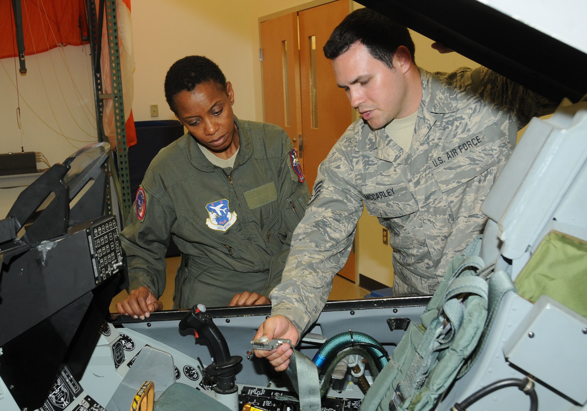 Staff Sgt. Jesse McCarley, 121st Fighter Squadron survival and egress instructor, 113th Wing, demonstrates to Rep. Donna Edwards the use of a seatbelt on an F-16C Fighting Falcon simulator prior to Edwards’ ride aboard the real thing at Joint Base Andrews, June 29, 2011. This was the congresswoman’s first time aboard a fighter jet, a life-long desire she held since she was a young daughter of an Air Force veteran. (U.S. Air Force photo/Tech Sgt. Craig Clapper/Released)