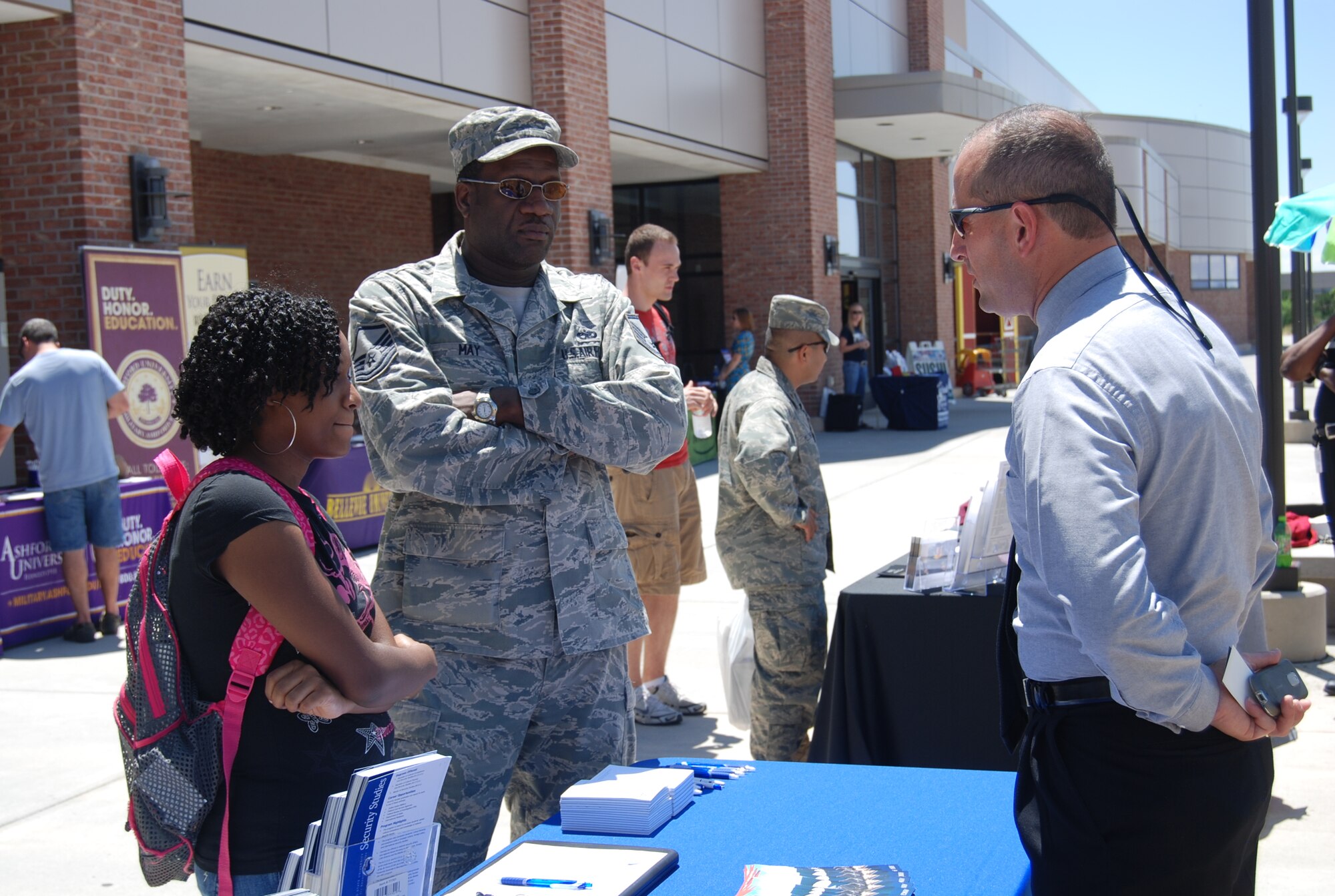 Master Sgt. Kenneth May and his daughter Kensi May visit with a college representative at the education fair July 13, 2011, at the Peterson Base Exchange. All schools at the fair had to meet national accreditation requirements and be military friendly institutions. (U.S. Air Force photo/Lea Johnson)