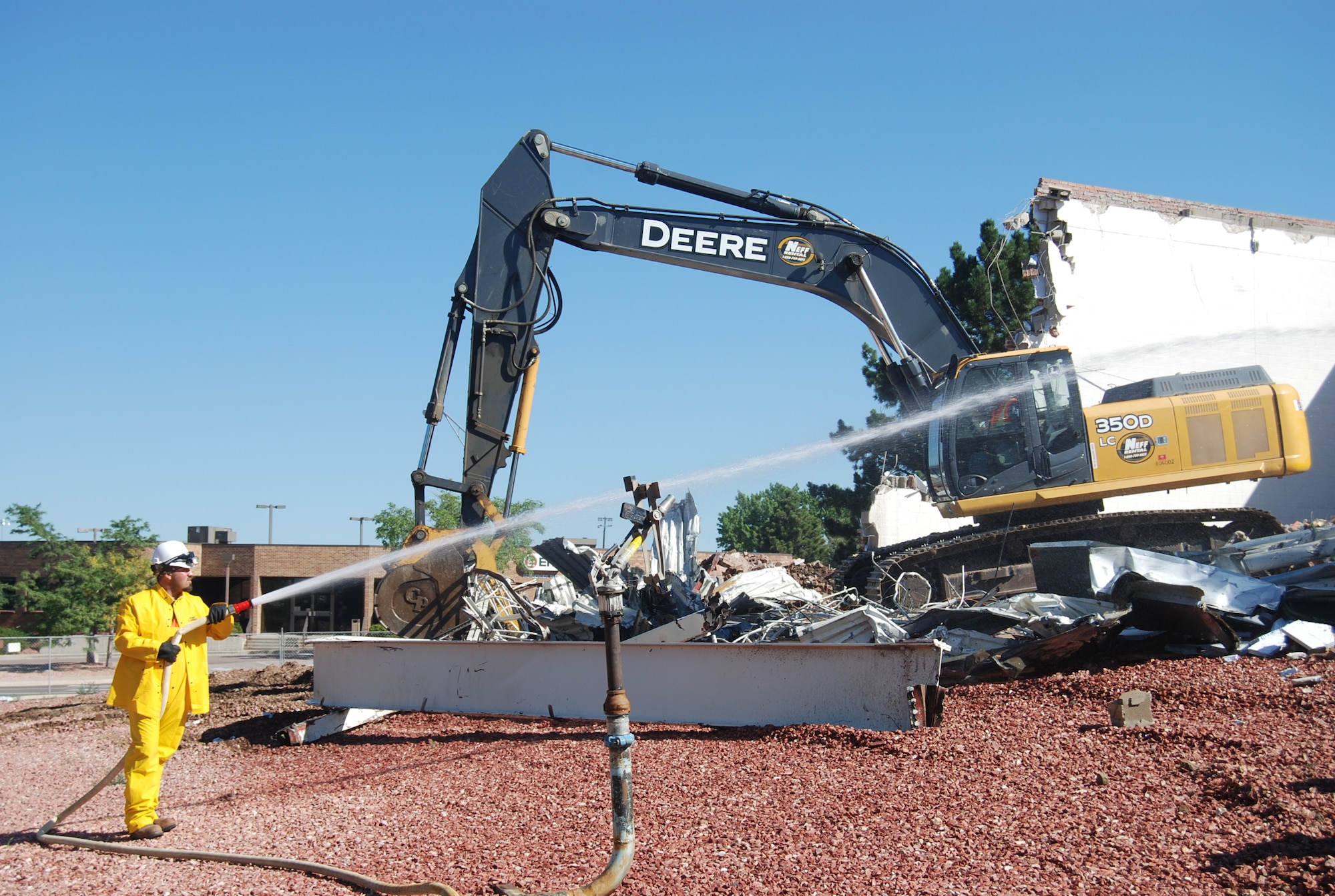 A construction worker sprays water to keep the debris down during the old commissary deconstruction. The goal is to recycle 50 percent of the building. The project is anticipated to be completed by Aug. 19. (U.S. Air Force photo/Lea Johnson)