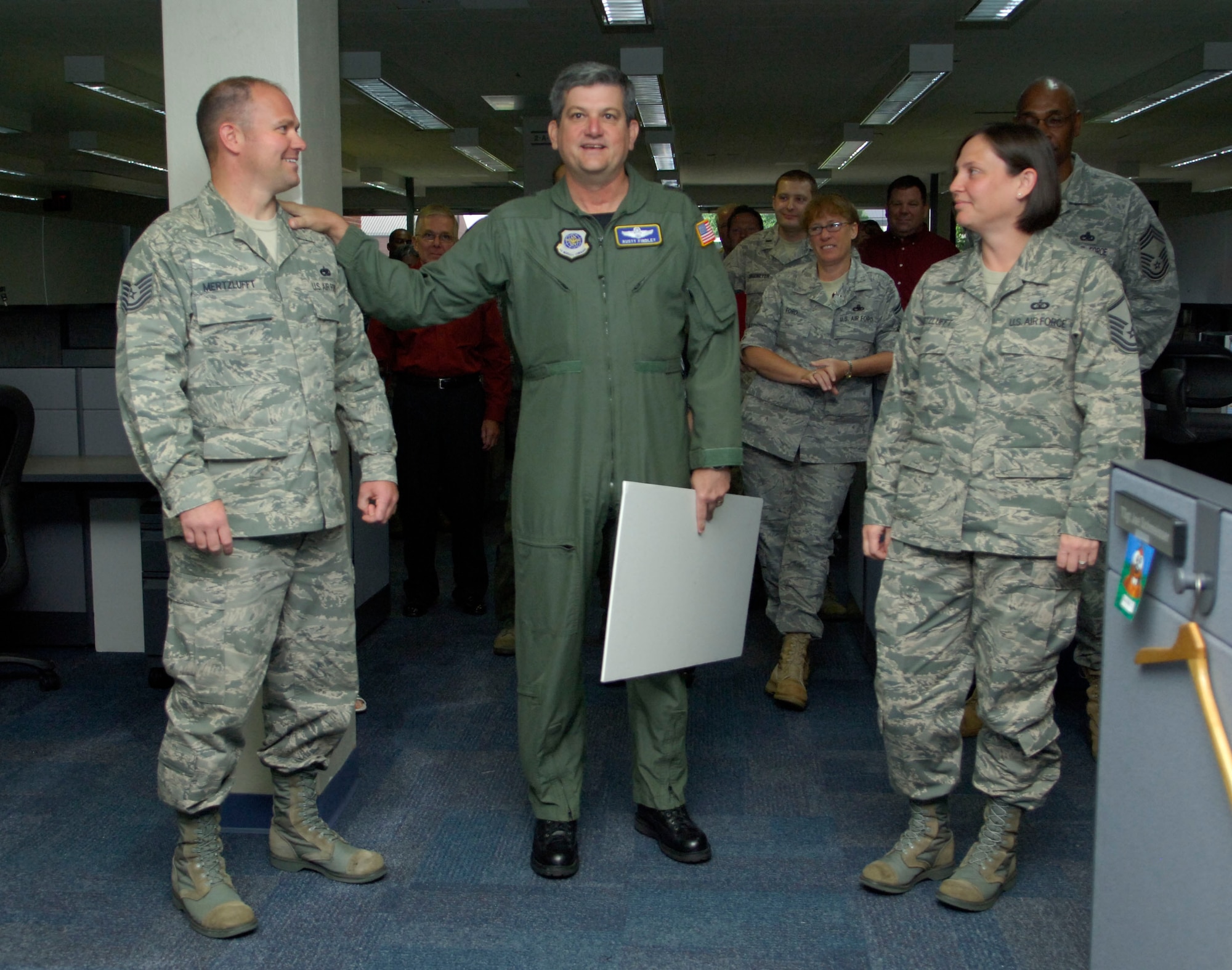 Tech. Sgt. Bryan Mertzlufft, Air Mobility Command warfare systems (left), is presented a check for $10,000 July 22 by Lt. Gen. Rusty Findley, vice commander of Air Mobility Command, while his wife, Master Sgt. Molly Mertzlufft, Air Mobility Command, watches.  Mertzlufft was awarded the incentive check through the Air Force Innovative Development through Employee Awareness, or IDEA, program. (U.S. Air Force photo/ Samantha Crane)