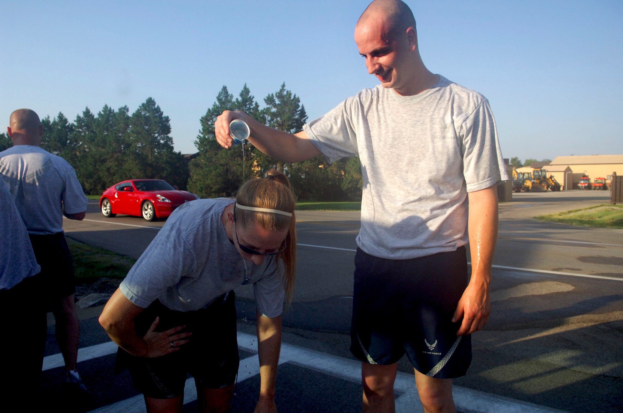 Tech. Sgt. Addison Coyler helps Staff Sgt. Leasa Craver cool off by pouring water on her neck after a morning run with the 375th Civil Engineer Squadron July 22. (U.S. Air Force photo/ Samantha Crane)