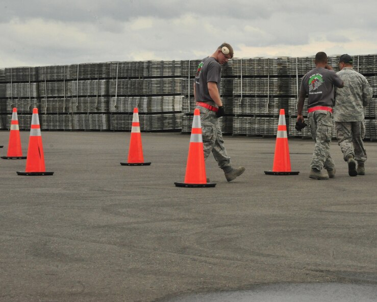 A Rodeo umpire walks Staff Sgts. Chris Lenane and Chris Johnson, 62nd Aerial Port Squadron Rodeo team members, through the 10K forklift obstacle course prior to the competition July 25, 2011 during Air Mobility Rodeo 2011, at Joint Base Lewis-McChord, Wash. There were more than 20 three-foot orange cones that made up the course in addition to a pallet stacking portion. (U.S. Air Force Photo/Staff Sgt. Frances Kriss) 