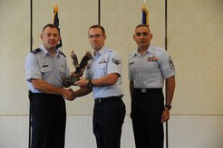 Col. Richard McComb and Chief Master Sgt. Jose LugoSantiago present Senior Airman Steven Williams a statue in recognition of his being selected as a 628th Air Base Wing quarterly award winner, July 25 at Joint Base Charleston – Air Base. Other 628 ABW quarterly award winners included Senior Airman Laura Yang, Staff Sgt. Tahara Burchell, Master Sgt. Diana Tamayo, 1st Lt. Ryan Peake, Capt. Aaron Cohenour, Airman 1st Class Pativa Brice, Paul Valentine and Cheryl Bennett. McComb is the Joint Base Charleston commander, LugoSantiago is the 628 ABW command chief and Williams is assigned to the Honor Guard. (U.S. Air Force photo/Staff Sgt. Nicole Mickle)