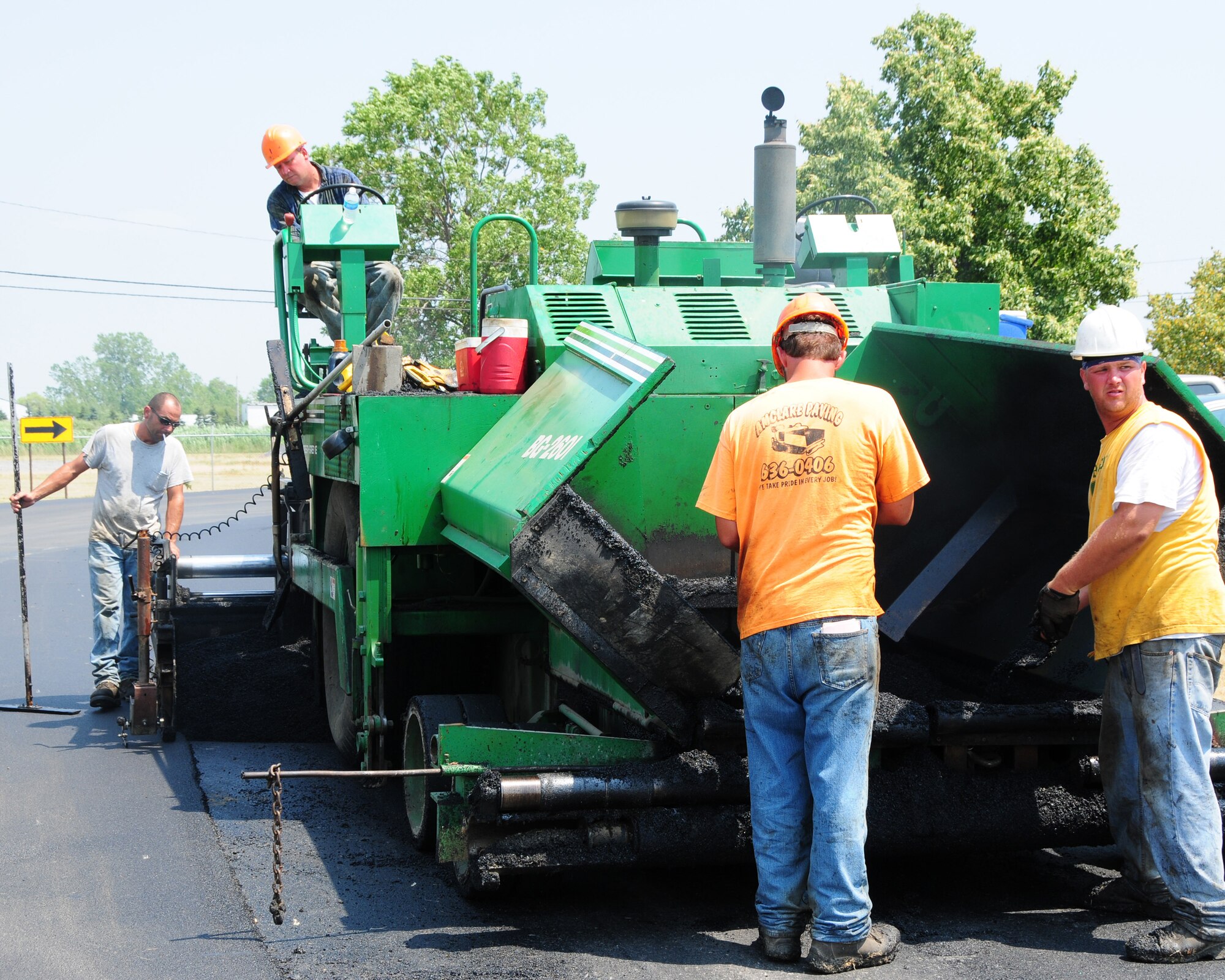 A road paving crew puts another layer of asphalt down on Kirkbridge Drive in front of the 914th Airlift Wing headquarters building.  This was just one of many base roadways and parking lots that needed to be resurfaced.  This project is expected to be completed by the beginning of August of this year. (U.S. Air Force photo by Peter Borys)