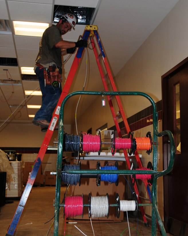 An electrician, one of many construction workers on base is feeding wire up through the ceiling for light fixtures that will be installed throughout the Community Activities Center.  This is just one of many construction projects that are underway currently on base.  The 18,000 square foot facility is expected to be completed during August of this year. (U.S. Air Force photo by Peter Borys)