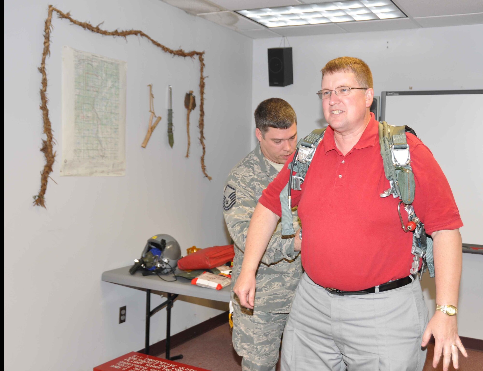 Master Sgt. Darren Wilson helps David Downing, 934th Operations Group honorary commander, try on a parachute during the Base Community Council tour July 22. (Air Force Photo/Paul Zadach)