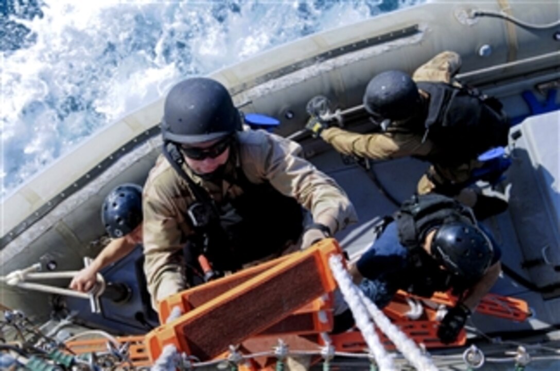 A U.S. Navy sailor climbs from a rigid-hull inflatable boat to the weather deck of the USS Curtis Wilbur (DDG 54) after a visit, board, search and seizure drill in the Timor Sea on July 21, 2011.  The Curtis Wilbur is participating in Talisman Saber 2011, a bilateral exercise intended to train Australian and U.S. forces in planning and conducting combined task force operations.  