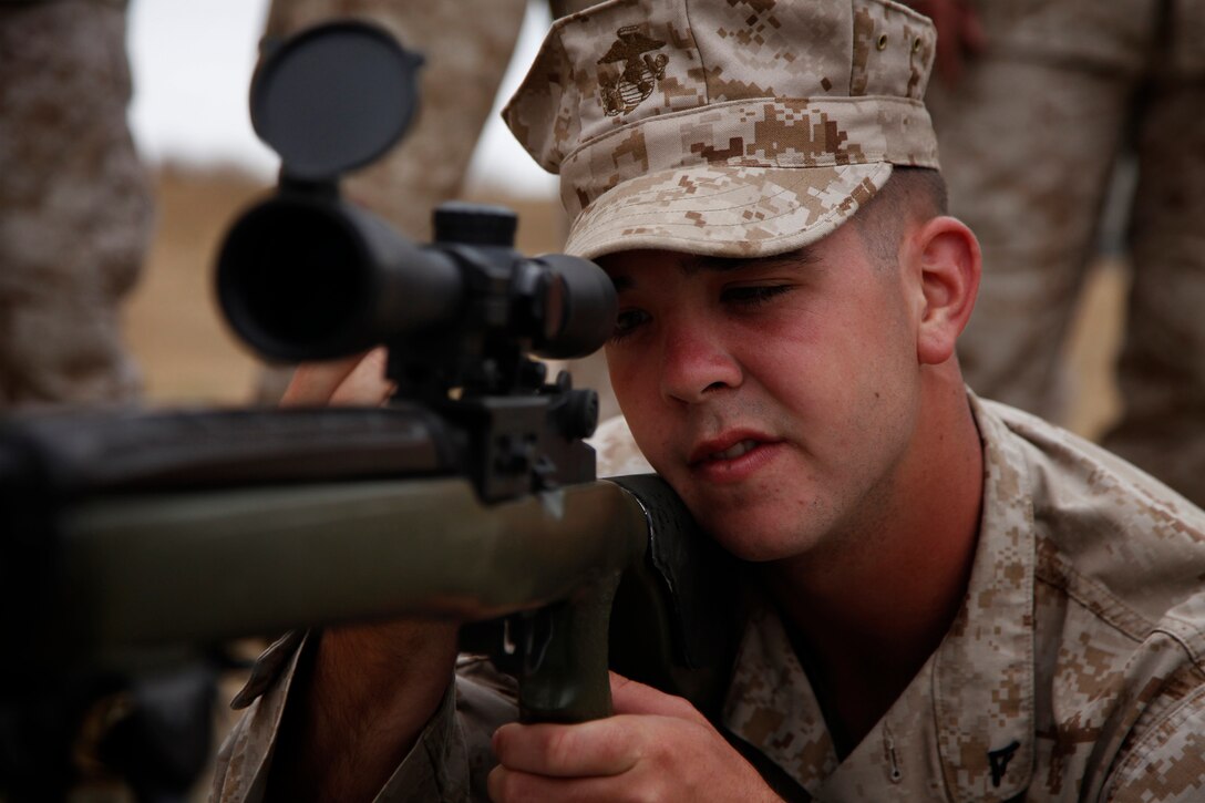 Lance Cpl. John H. Fulton, administrative clerk, 15th Marine Expeditionary Unit (MEU) looks down the sights of a Designated Marksman Rifle as a part of a familiarization fire range conducted on Camp Pendleton, July 26-27. Fulton, 20, is a native of Howell, N.J. and has already completed a deployment with the unit and is eagerly looking forward to his next float.