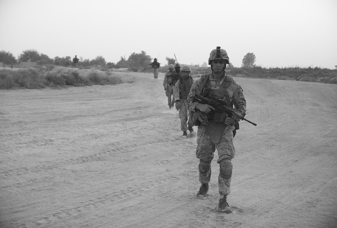 Steve Toth walks across a road while on a security patrol here, July 27. Toth, a native of Spring Valley, N.Y., is a law enforcement professional with 1st Battalion, 3rd Marine Regiment. Marines with 1/3 ensure security of the district by patrolling everyday with their Afghan National Army counterparts. The battalion supports Regimental Combat Team 1, under 2nd Marine Division (Forward), which serves as the ground combat element in Helmand. The mission of the division is to partner with Afghan National Security Forces to conduct counterinsurgency operations to secure the Afghan people, defeat insurgent forces, and enable ANSF to assume security responsibilities in the region. Ultimately, the partnered forces promote the expansion of stability, development and legitimate governance.