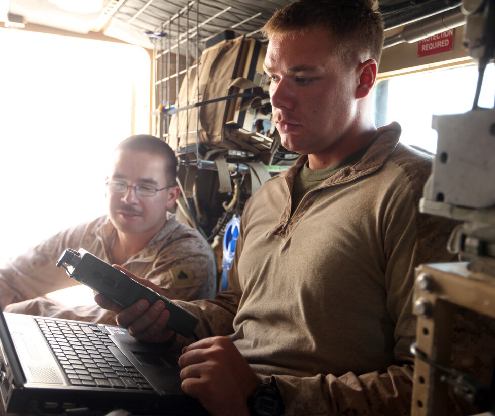 Lance Cpl. Charles Shoenfelt (foreground) and Cpl. Andrew Black (background), both ground radio intermediate repairers with 2nd Marine Logistics Group (Forward), install upgrades on a radio at Forward Operating Base Marjah, Afghanistan, July 28, 2011. Shoenfelt and Black are part of a three-man communication team that travels around Helmand province maintaining radios and other communication devices for explosive ordnance disposal teams.