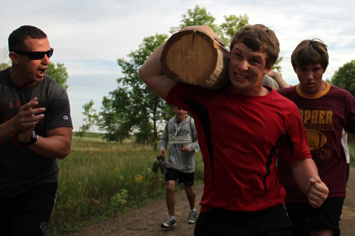 All-Marine wrestler Cpl. Daniel SotoNieves motivates Brendon Swartz, a South Dakota state qualifier at 130 pounds from Roosevelt High School, and Hunter Durand, a varsity wrestler from Buffalo, Minn., during a log race competition at the All-Marine Wrestling Camp July 28. For additonal imagery from the event, visit www.facebook.com/rstwincities.