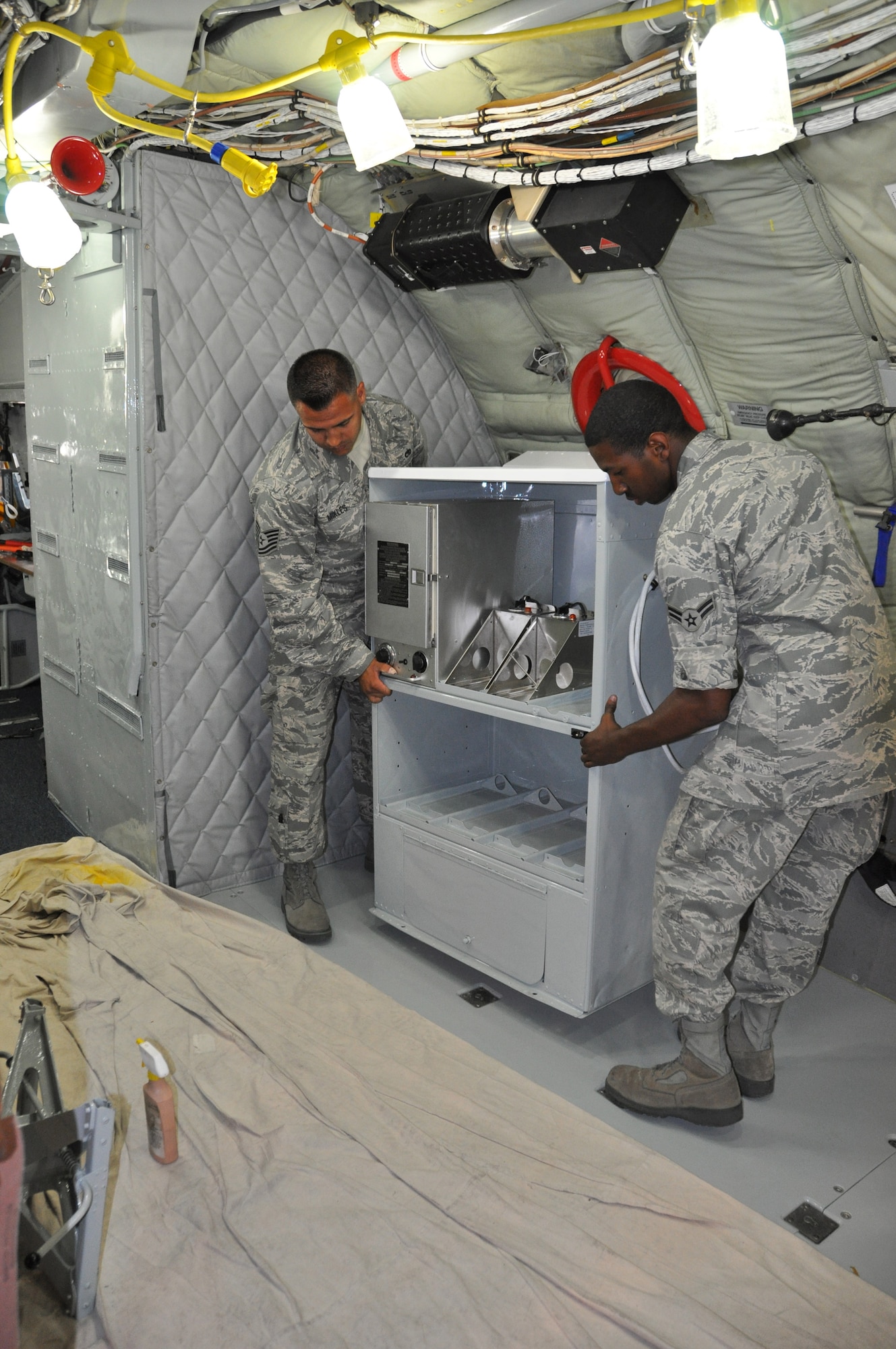 Tech. Sgt. Dana Mikles and Airman Kenneth Roy lower a refurbished galley into place inside a KC-135 Stratotanker at March Air Reserve Base, Calif., July 19, 2011. Airmen from the 452nd Maintenance  Group refurbished the interior of the 49-year-old aircraft in just 23 days. (U.S. Air Force photo/Megan Just)